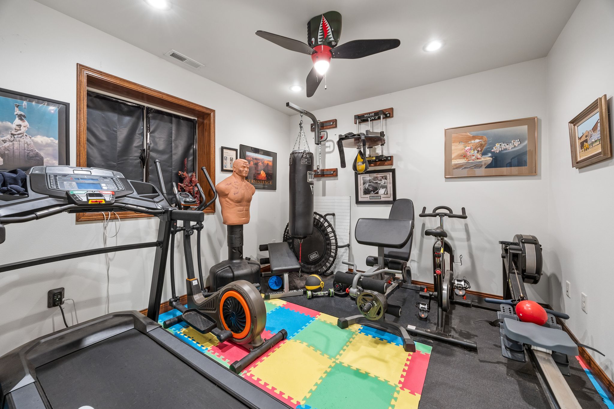 Basement exercise room with treadmill, elliptical, exercise bike, rowing machine, and punching bags